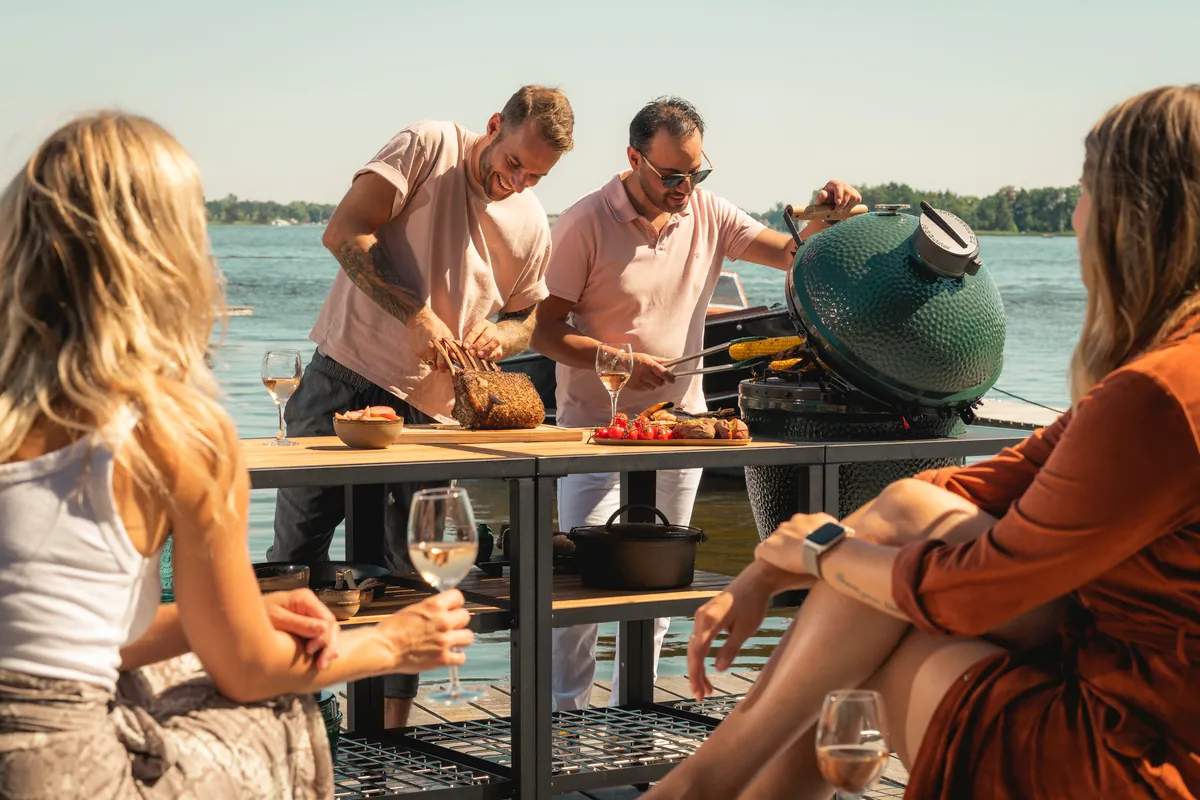 Grupo de amigos cocinando con un Big Green Egg junto al agua