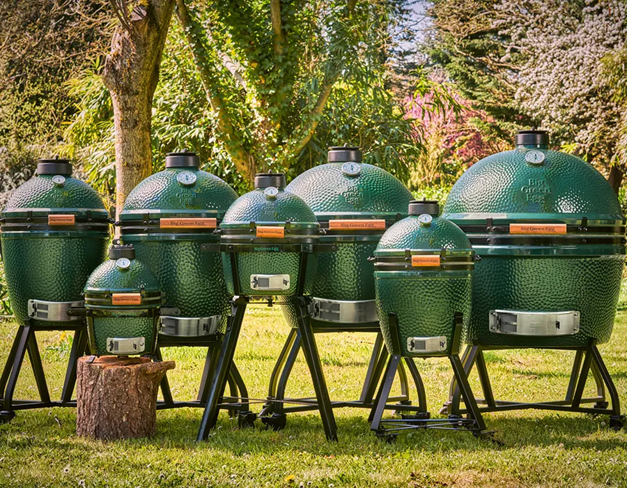 Siete Big Green Egg de distintos tamaños en un jardín